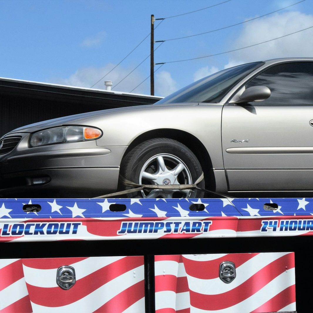 a flatbed tow truck with a silver car on it