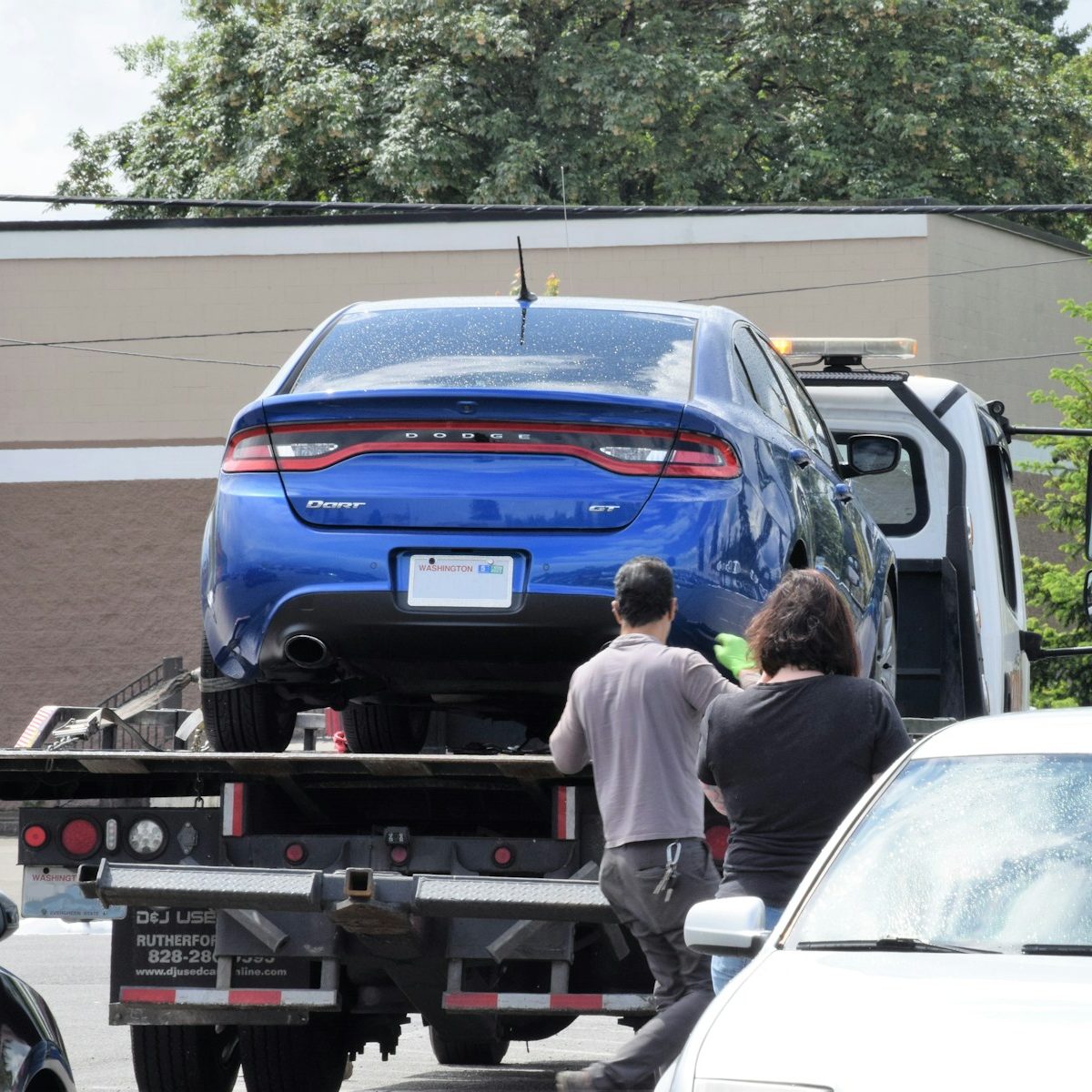 a blue car being loaded onto a flatbed truck
